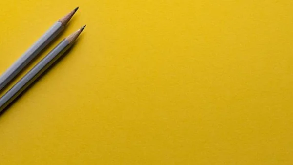 Two pencils on yellow background